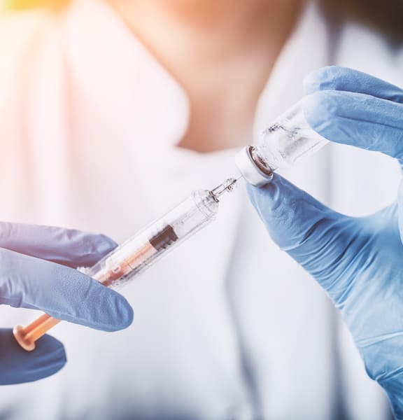 Врач держит в руках шприц и лекарство